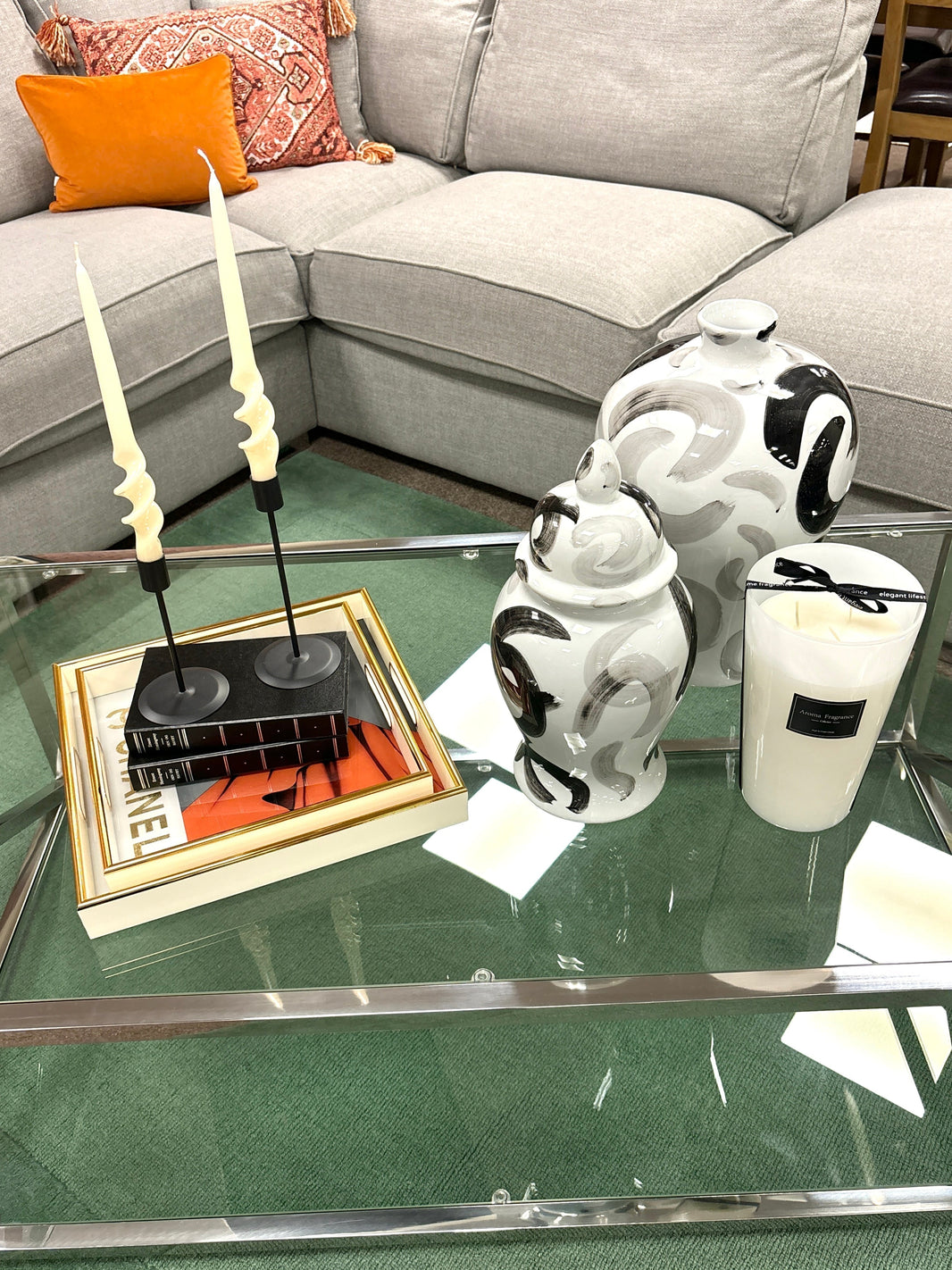 A glass and metal coffee table featuring accessories from Mi Casa Home