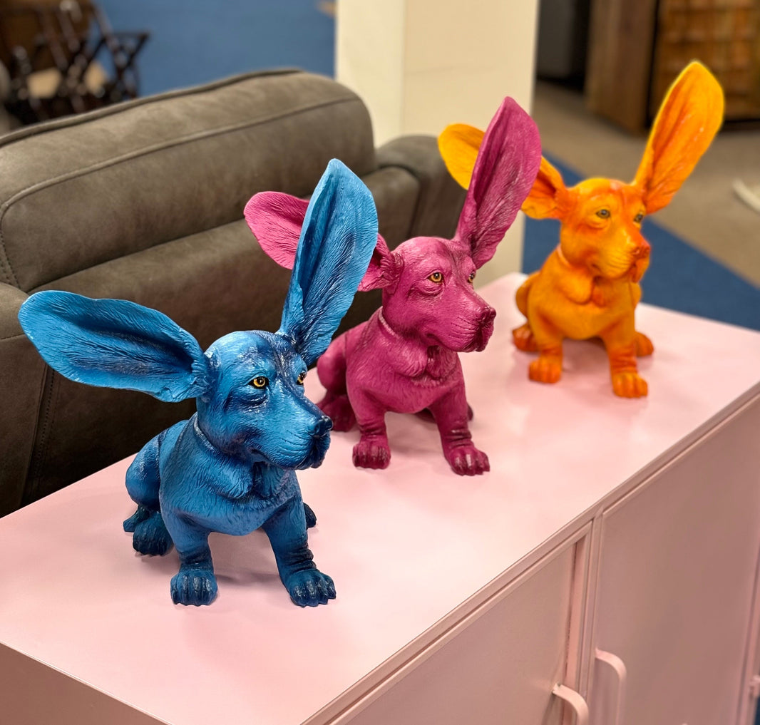 Blue, pink and orange decorative basset hound dog ornaments displayed on a sideboard