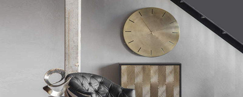 a modern, minimal gold wall clock in a living room.