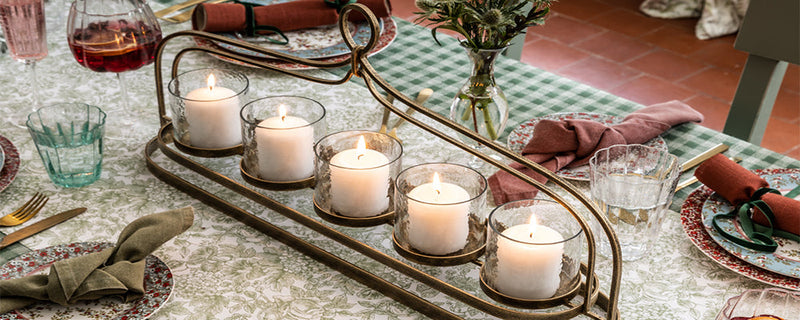 a metal decorative candle holder with five candles sits on a dining table