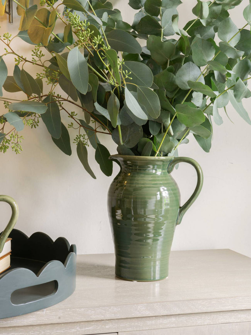 artificial plants stems and artificial flowers in a green vase.