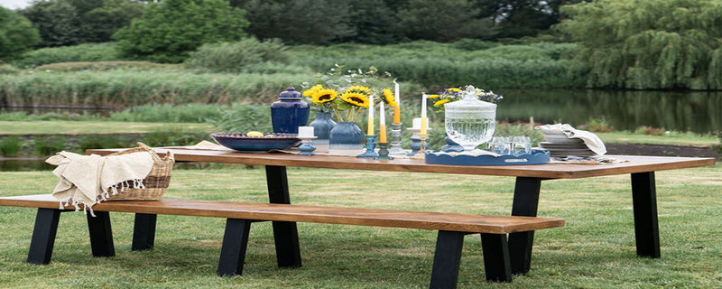 An outdoor picnic table set up with tabelware and glassware 