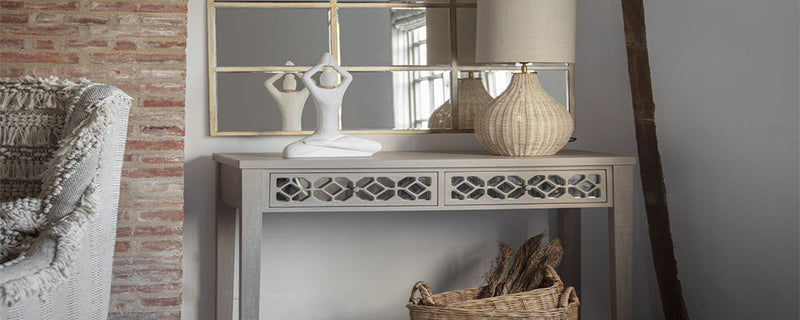 A narrow hallway console table styled with a lamp and figurine.
