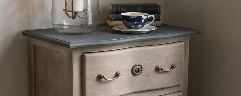 A wooden bedside cabinet with a drawer and two handles