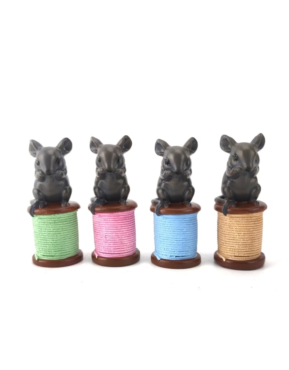 Four small animal figurines on colorful spools of thread 