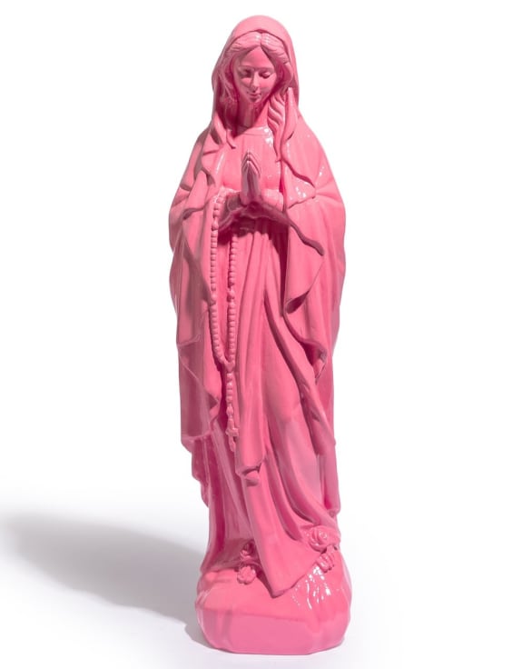 A pink religious figurine of the Virgin Mary, depicted in a prayer pose with rosary.