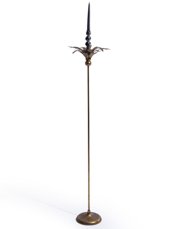 A tall brass candlestick holder with a decorative palm tree top 