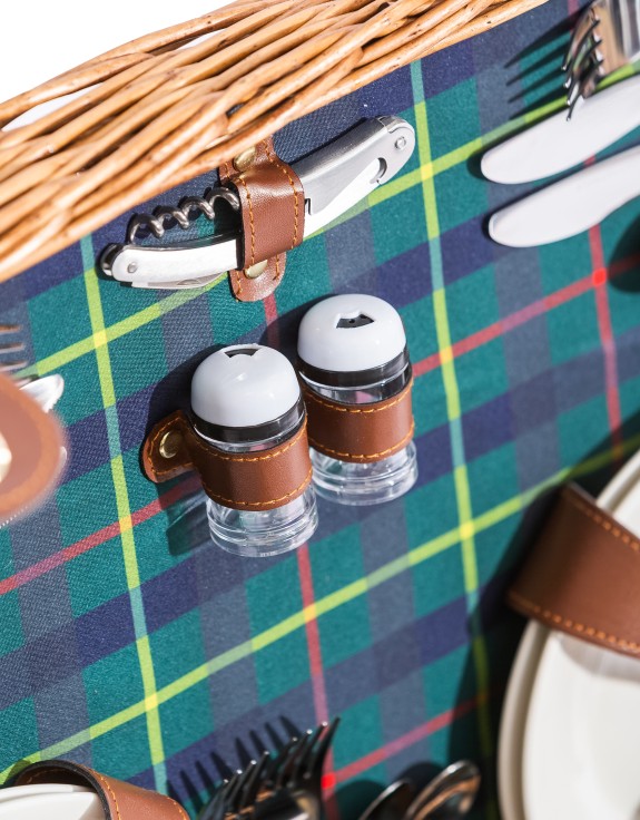 Salt and pepper shakers secured with brown leather straps in a picnic hamper with tartan lining