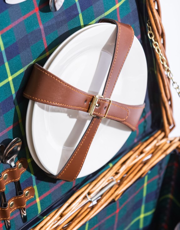 Picnic plates secured with brown leather straps in a picnic hamper with tartan lining