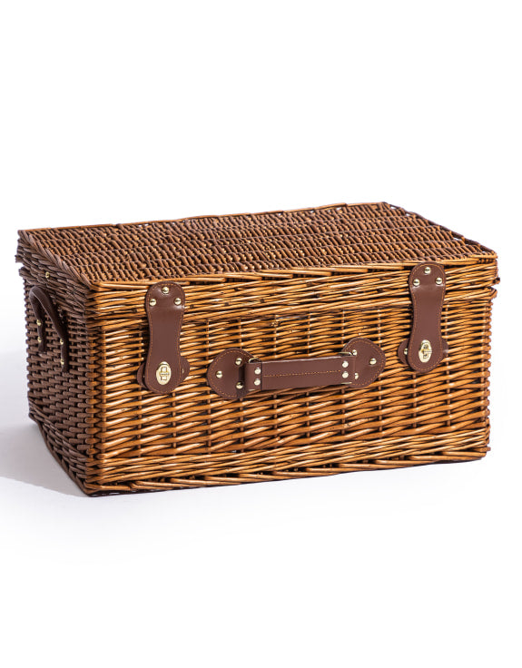 Luxury wicker picnic hamper closed with leather straps on a white background