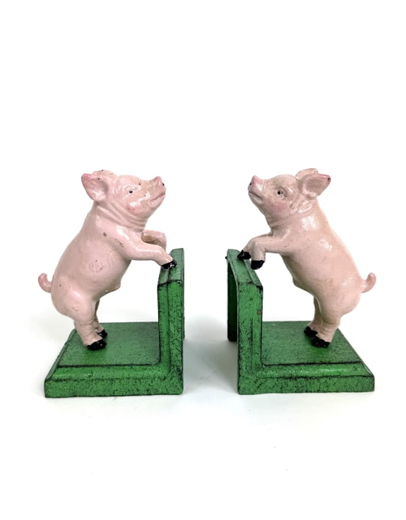 A pair of pig bookends featuring light pink pig figurines standing on green rectangular bases, photographed against a plain white background.